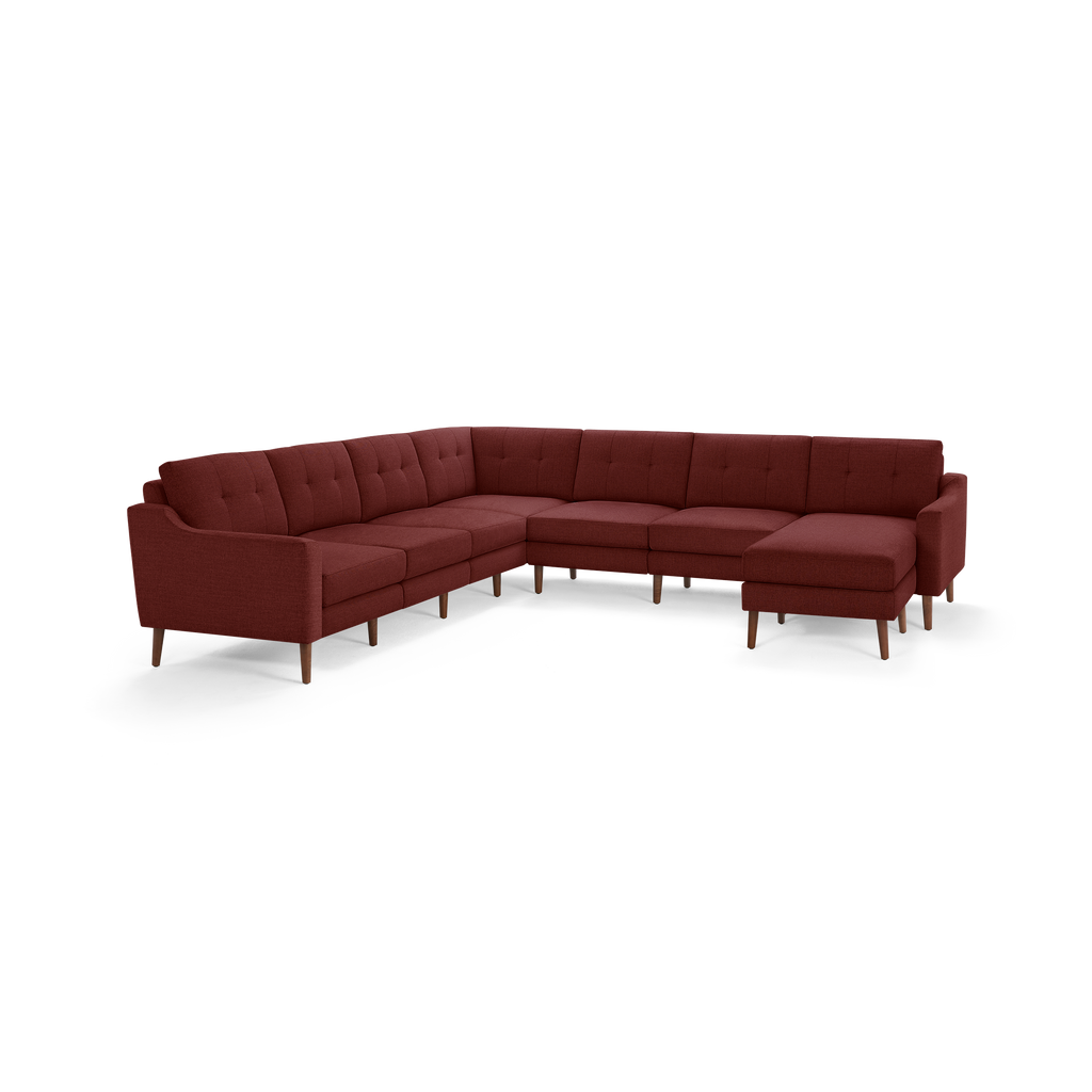 Large L-shaped sectional sofa in deep burgundy fabric with tufted back cushions and wooden tapered legs.