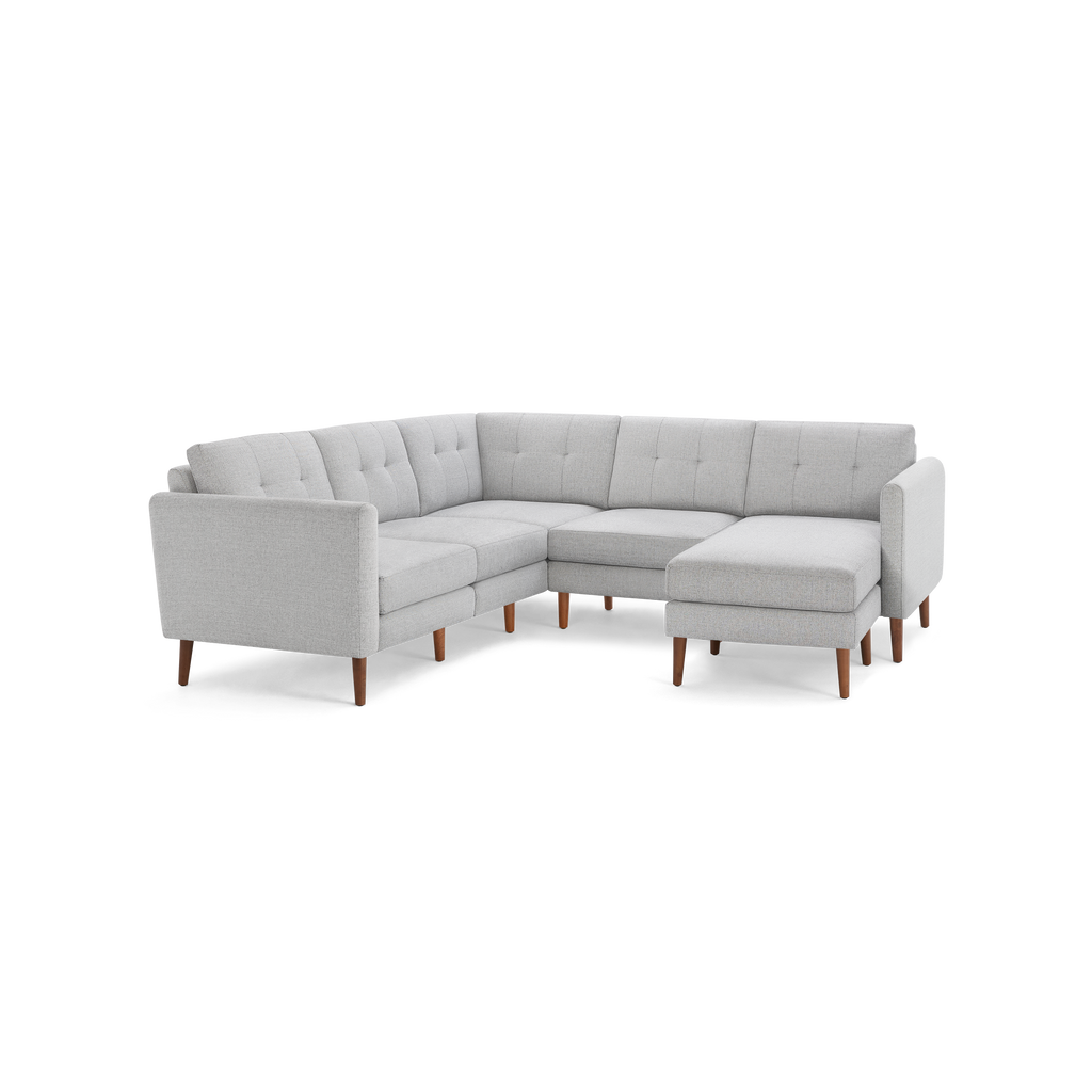 Light gray upholstered sectional sofa with tufted cushions and wooden legs, featuring a right-side chaise lounge.