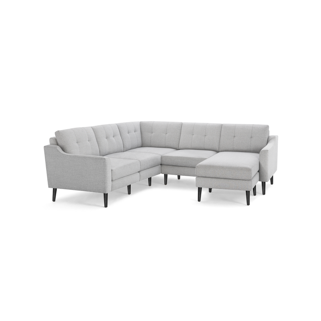 Light gray upholstered L-shaped sectional sofa with tufted back cushions and dark wooden legs, featuring a chaise lounge on one end.