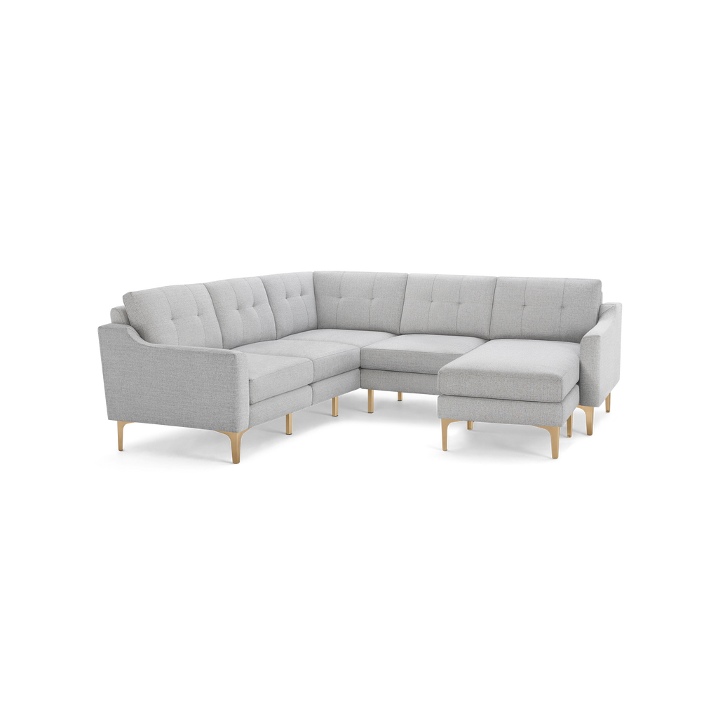 Light gray fabric L-shaped sectional sofa with tufted back cushions and light wooden angled legs.