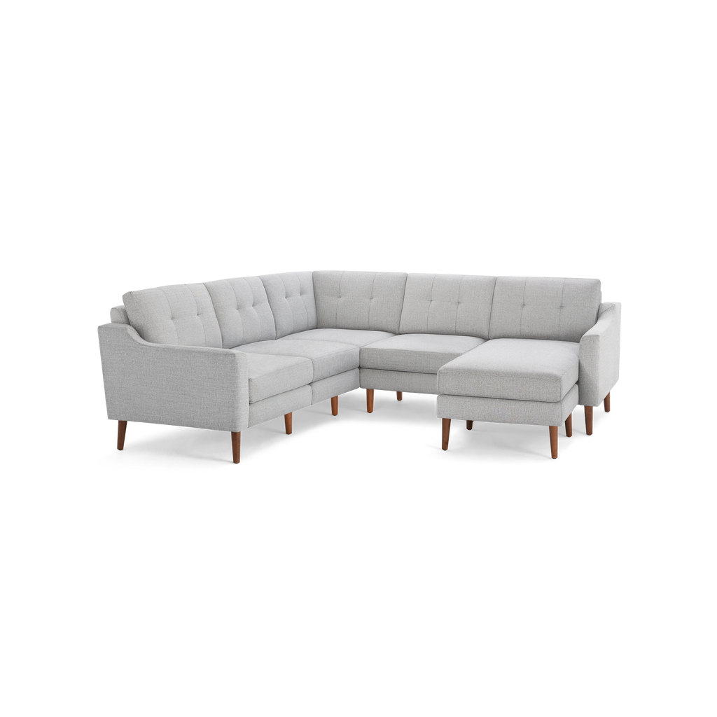 Light gray L-shaped sectional sofa with tufted cushions and mid-century modern wooden legs, featuring a chaise lounge on the right side.