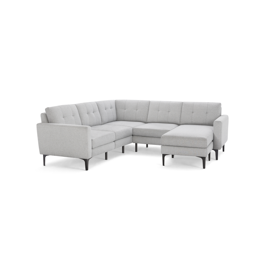 Light gray modern L-shaped sectional sofa with tufted cushions, slim black legs, and a chaise lounge on the right side.