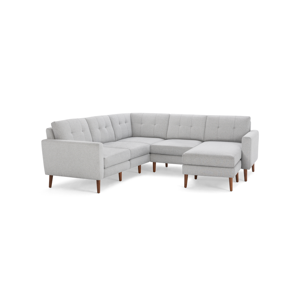 Light gray upholstered L-shaped sectional sofa with tufted back cushions and wooden tapered legs.