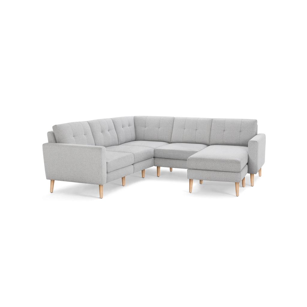 Light gray fabric sectional sofa with tufted back cushions, wooden legs, and a right-side chaise lounge.