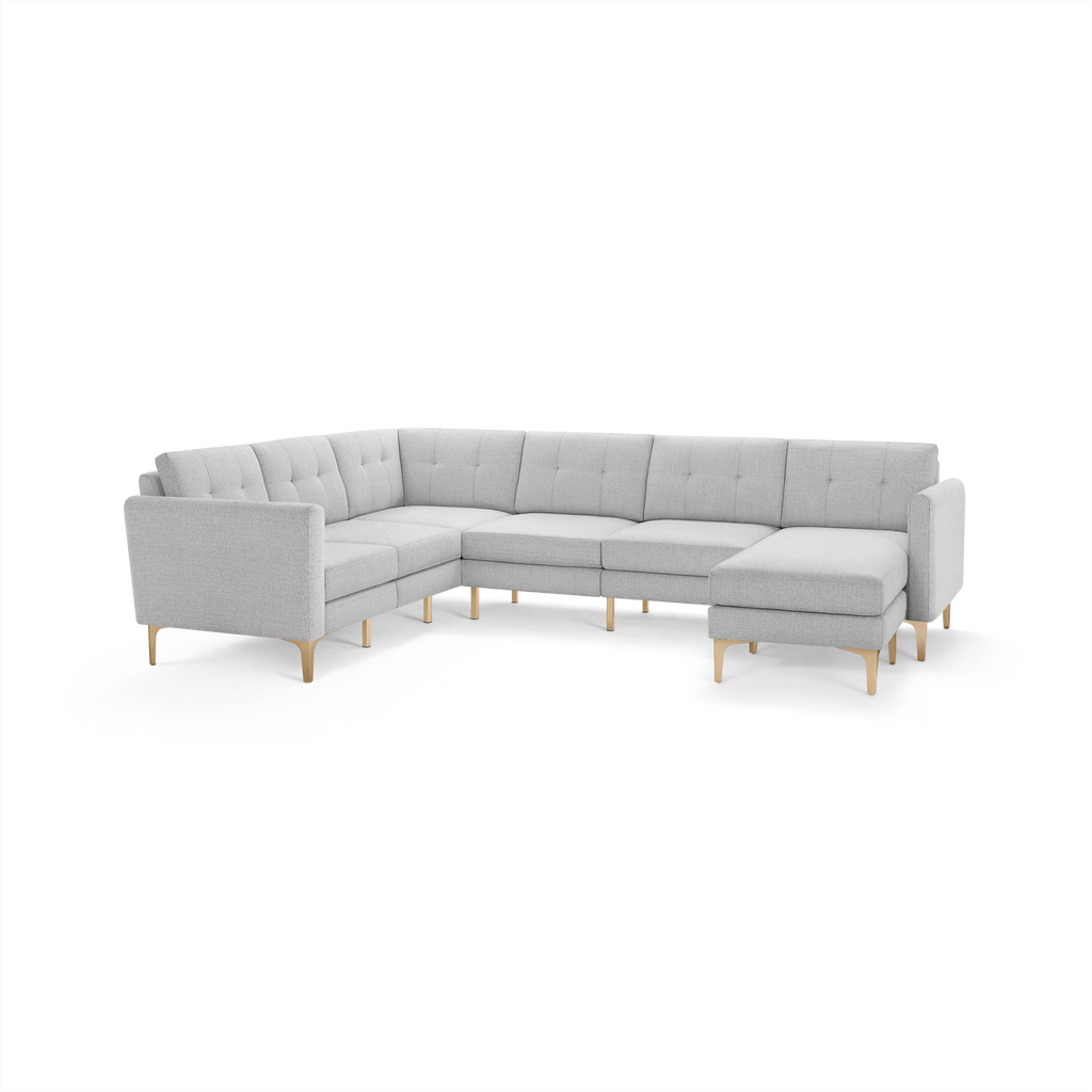 Light gray L-shaped sectional sofa with tufted back cushions and wooden legs, featuring a chaise lounge on the right side.