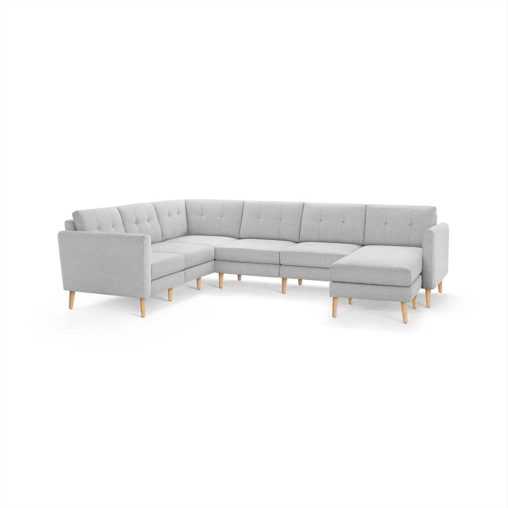 Light gray modern L-shaped sectional sofa with tufted back cushions and wooden angled legs, designed for spacious seating.