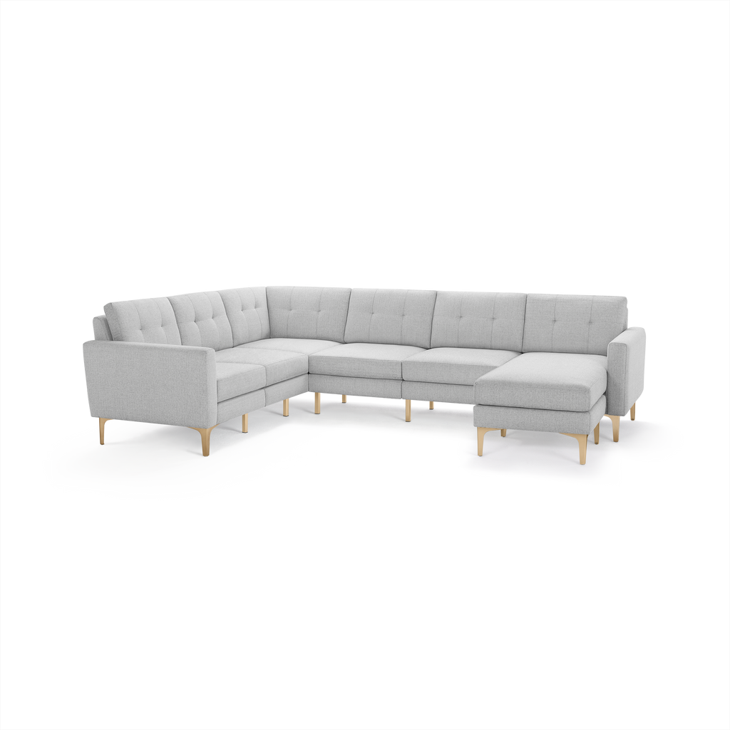 Light gray modern sectional sofa with tufted cushions, wooden legs, and an extended chaise lounge on the right side.