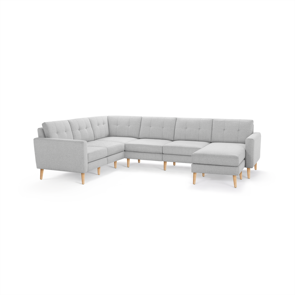 Light gray fabric L-shaped sectional sofa with tufted back cushions and natural wooden legs.