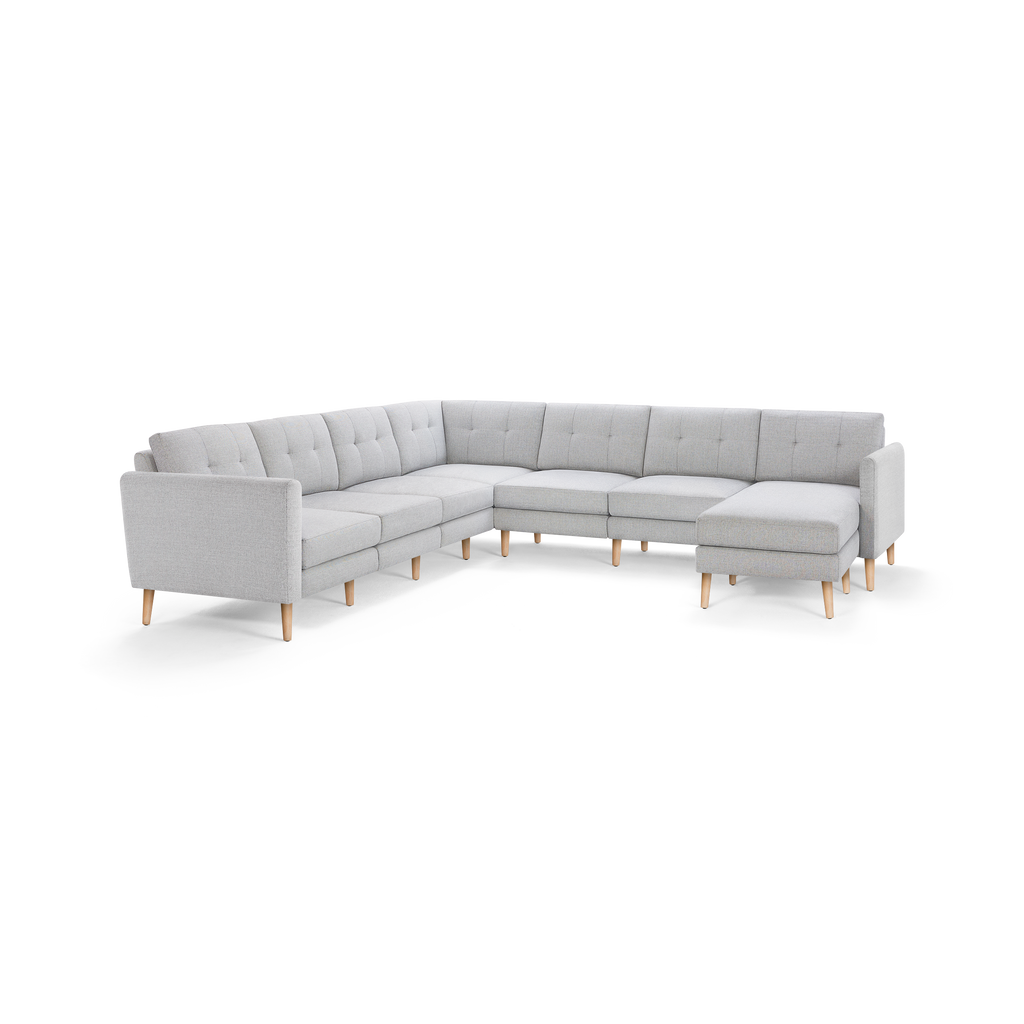 Light gray L-shaped sectional sofa with tufted back cushions and light wooden legs, offering modern and spacious seating.