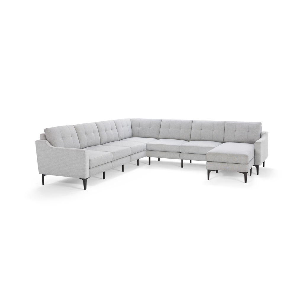 Light gray modern L-shaped sectional sofa with tufted back cushions, slim black legs, and a chaise lounge on the right side.