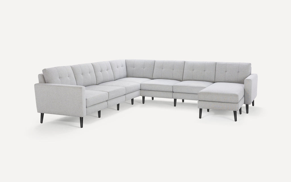 Light gray fabric sectional sofa with tufted back cushions and black tapered legs, featuring a chaise lounge on one end.
