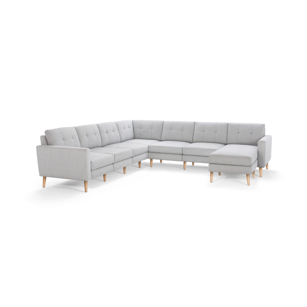 Light gray fabric L-shaped sectional sofa with tufted back cushions and wooden legs, featuring a chaise lounge on the right side.