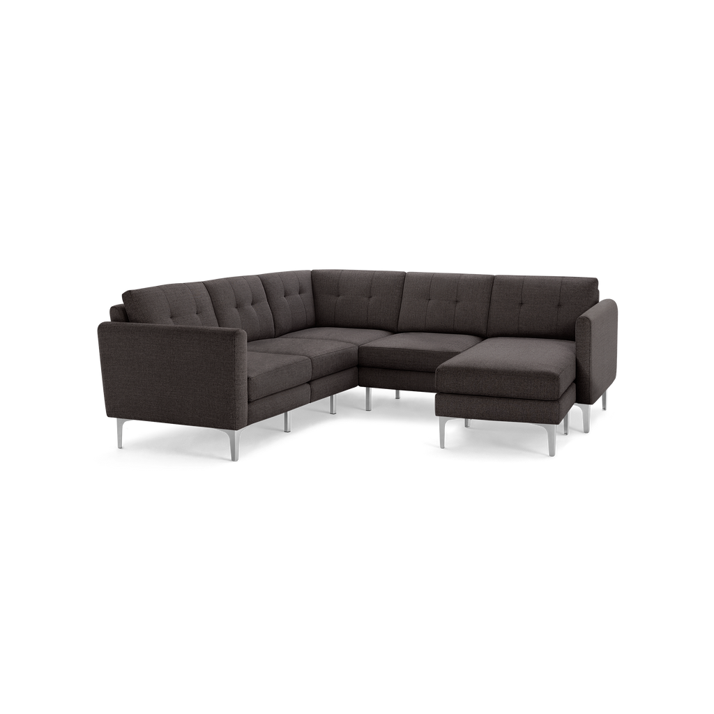 Dark gray fabric sectional sofa with tufted back cushions, angled arms, and sleek silver metal legs on a black background.