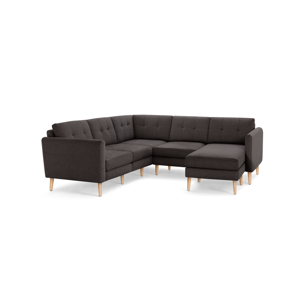 Dark gray L-shaped sectional sofa with tufted cushions and light wood legs, featuring a right-side chaise lounge.