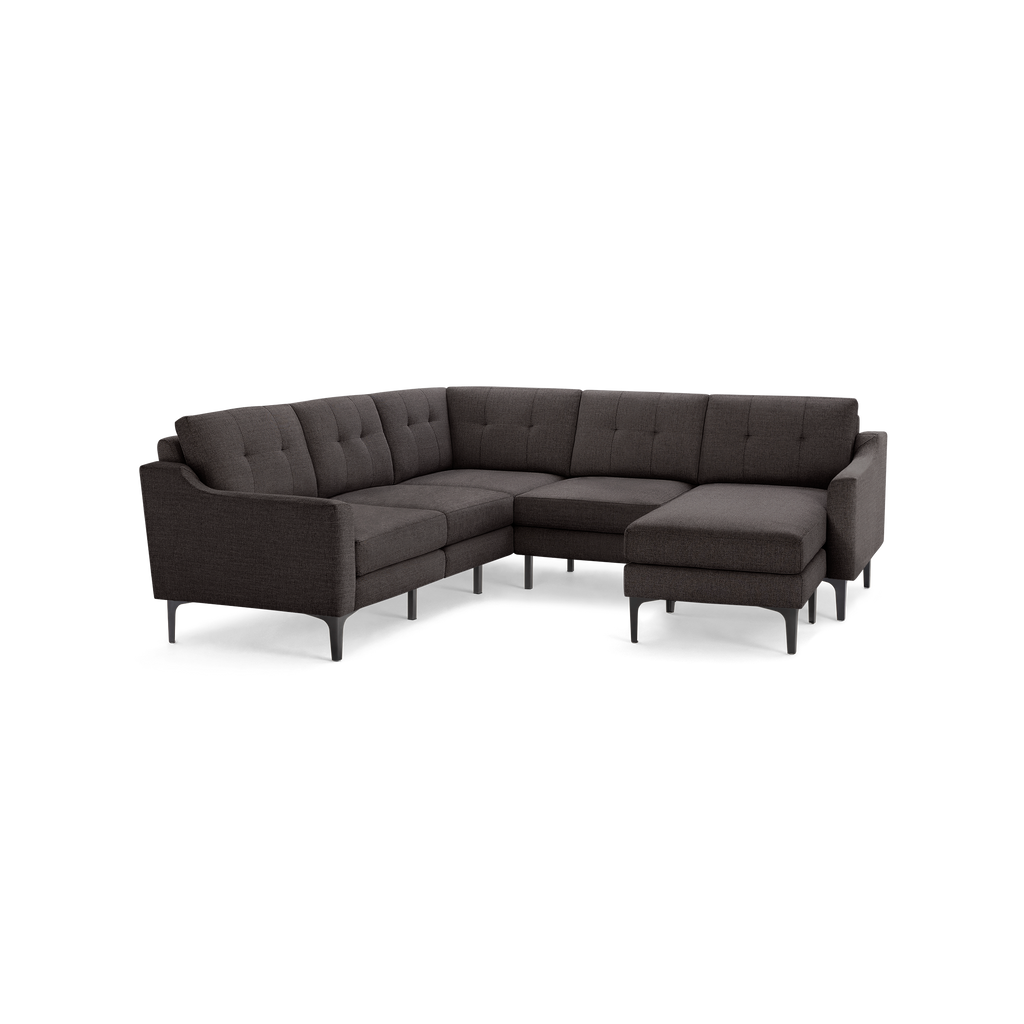 Dark gray L-shaped sectional sofa with tufted back cushions and slim black legs, featuring a chaise lounge on the right side.