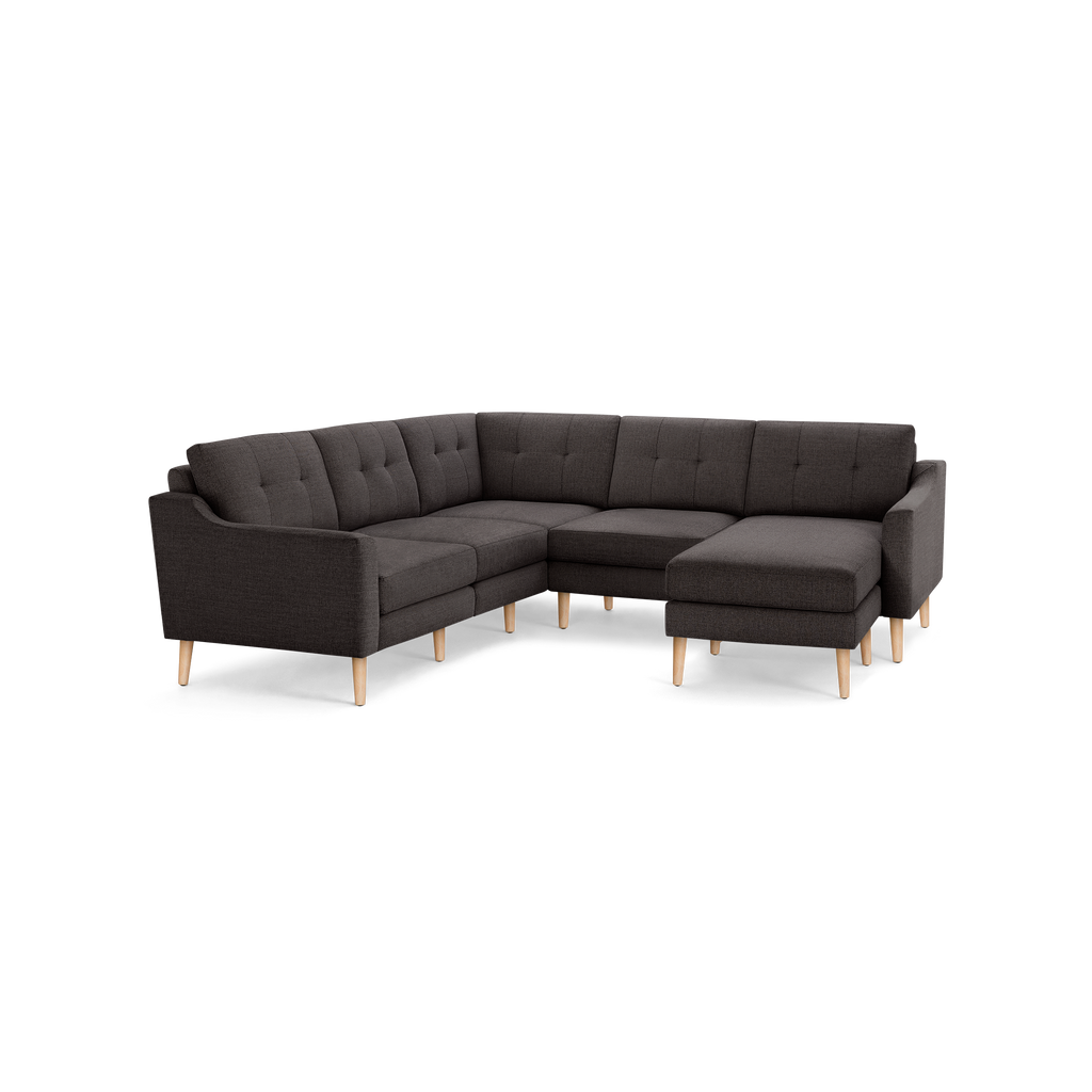 Dark gray fabric L-shaped sectional sofa with tufted back cushions and light wooden legs, designed for modern living rooms.