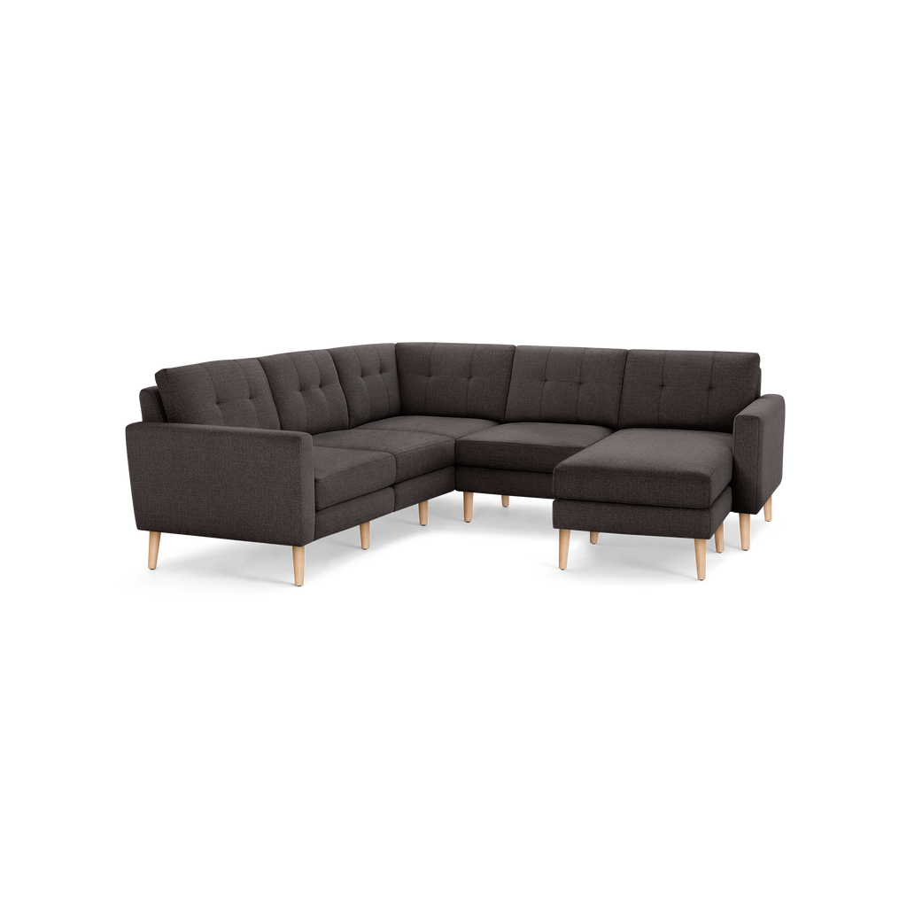 Dark gray L-shaped sectional sofa with tufted backrest, wooden legs, and a modern minimalist design.