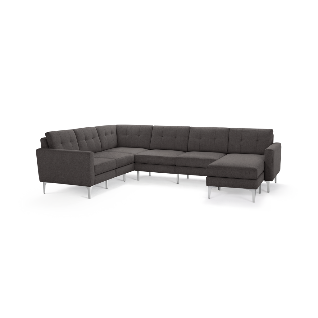 Dark gray modern sectional sofa with tufted cushions and sleek metal legs, designed in an L-shape with a chaise lounge on the right.