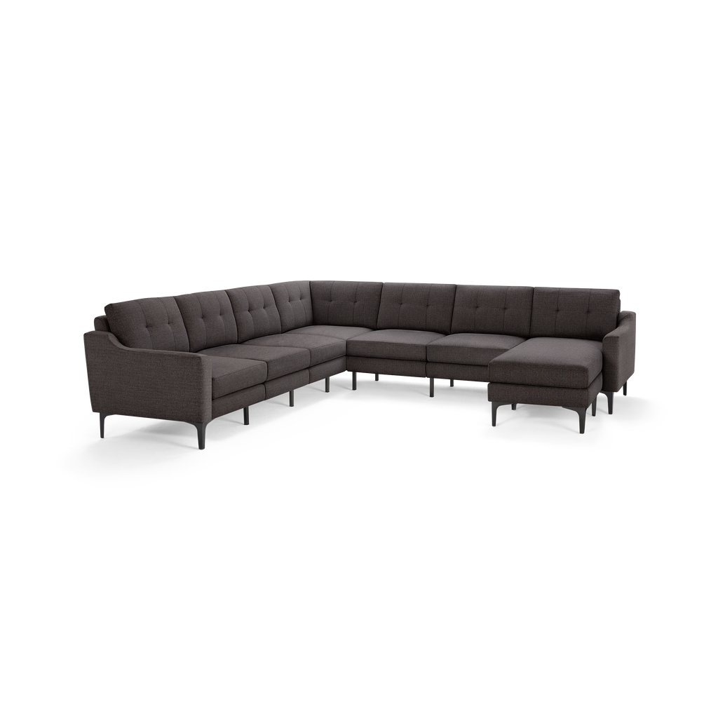Large dark gray upholstered sectional sofa with tufted back cushions and slim black legs, designed for corner placement.