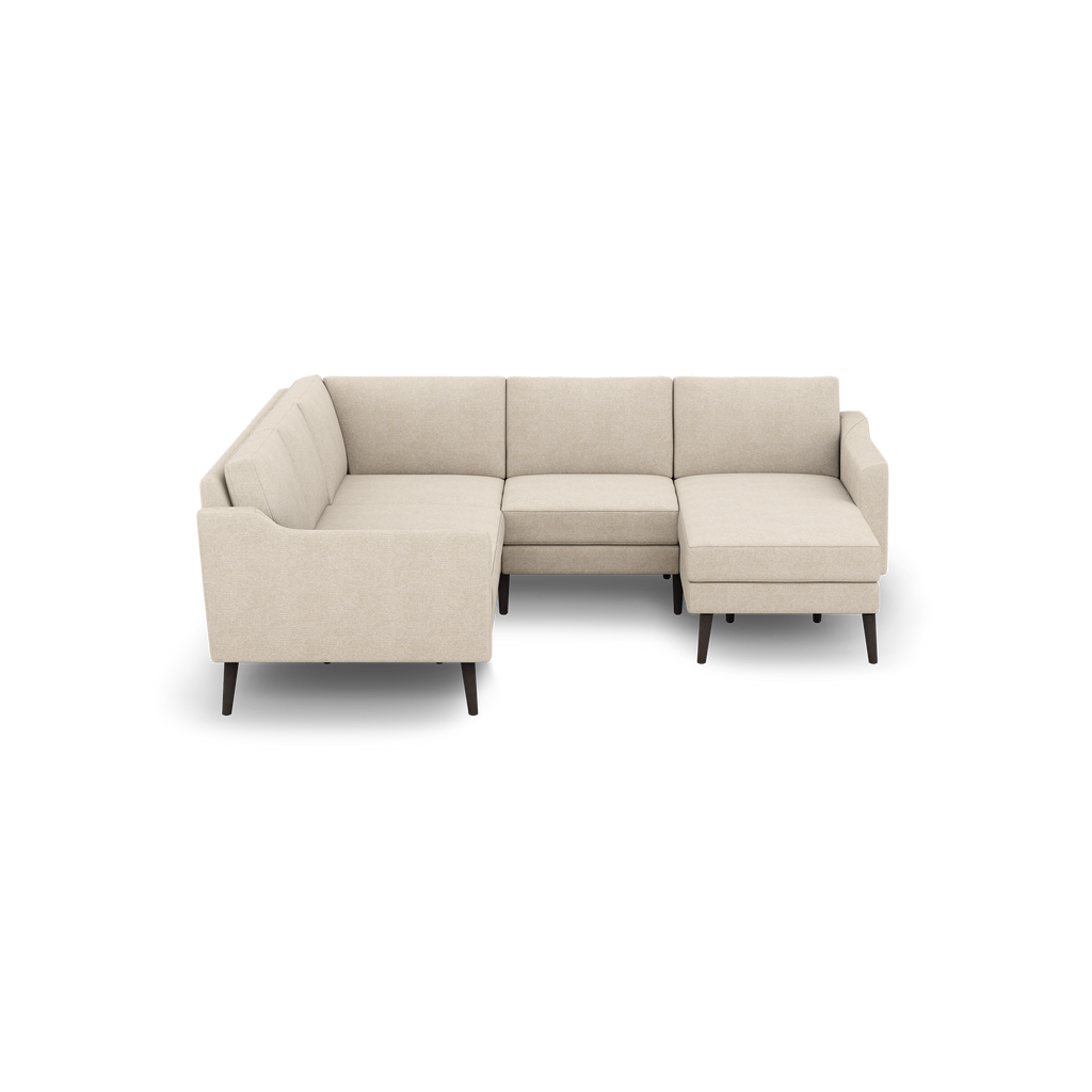 Beige fabric sectional sofa with left armrest chaise, cushioned seats, and dark wooden tapered legs against black background.