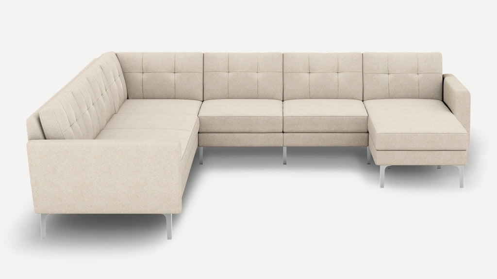 Beige L-shaped sectional sofa with tufted back cushions, slim metal legs, and a chaise lounge on the right side.