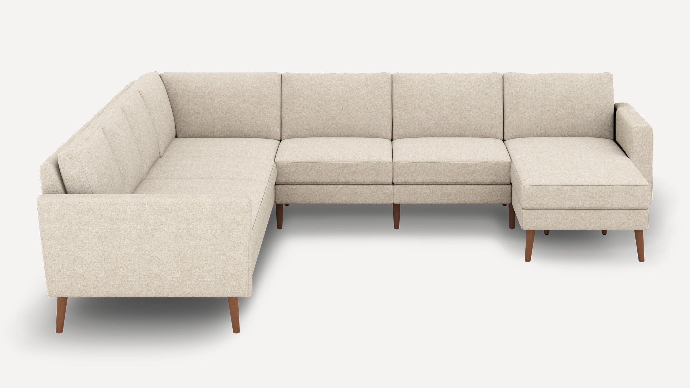 Modern beige L-shaped sectional sofa with wooden legs, tufted cushions, and a chaise lounge on the right side.