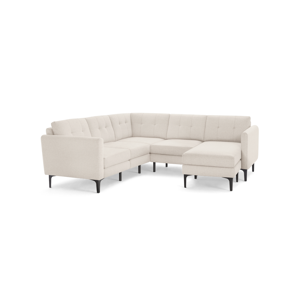 Light beige L-shaped sectional sofa with tufted back cushions and slim black metal legs on a white background.