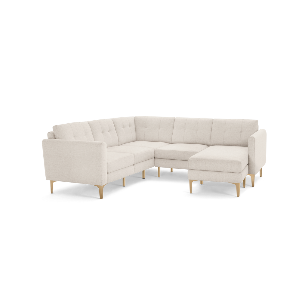 Cream-colored modern L-shaped sectional sofa with tufted cushions and light wooden legs on a black background.