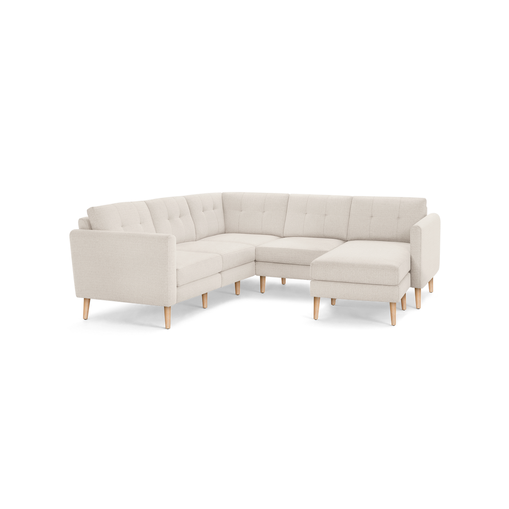 Light beige L-shaped sectional sofa with tufted back cushions and light wooden legs, modern minimalist design.