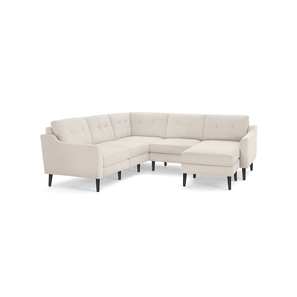 Light beige fabric sectional sofa with tufted back cushions, angled arms, and black tapered wooden legs.