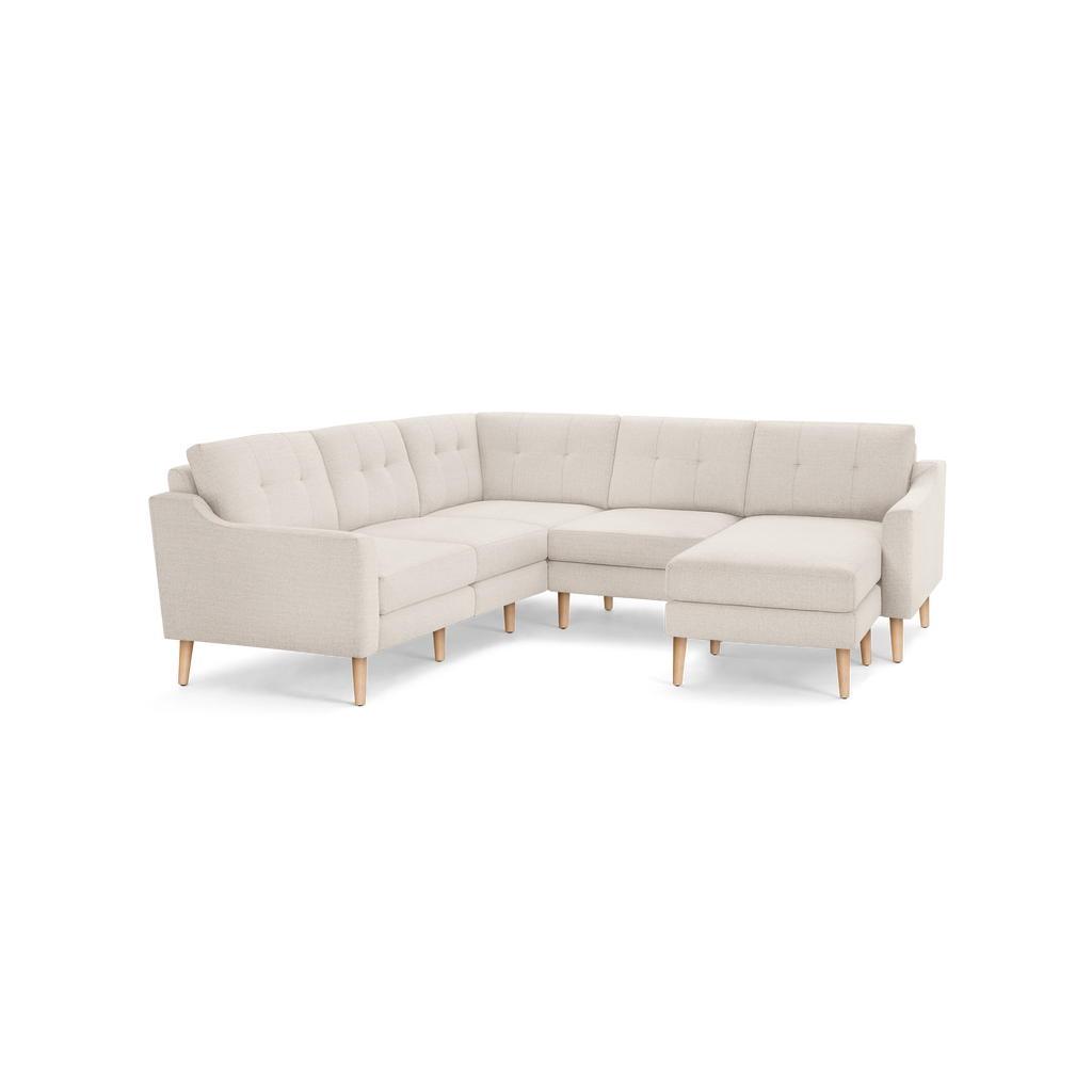 Light beige fabric sectional sofa with tufted back cushions, wooden legs, and a modern mid-century design.