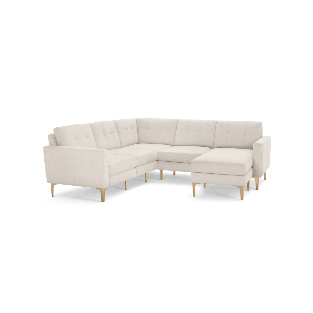 Modern L-shaped sectional sofa in light beige fabric with tufted back cushions and wooden tapered legs.