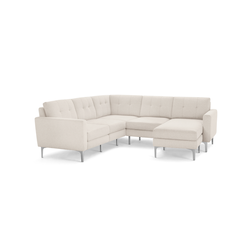 Cream-colored modern sectional sofa with tufted back cushions and slim metal legs, featuring a chaise lounge on the right side.