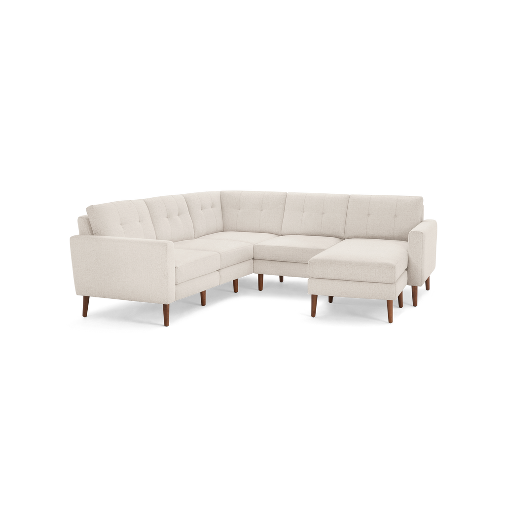 Beige fabric L-shaped sectional sofa with tufted cushions and wooden tapered legs, featuring an extended chaise on the right side.