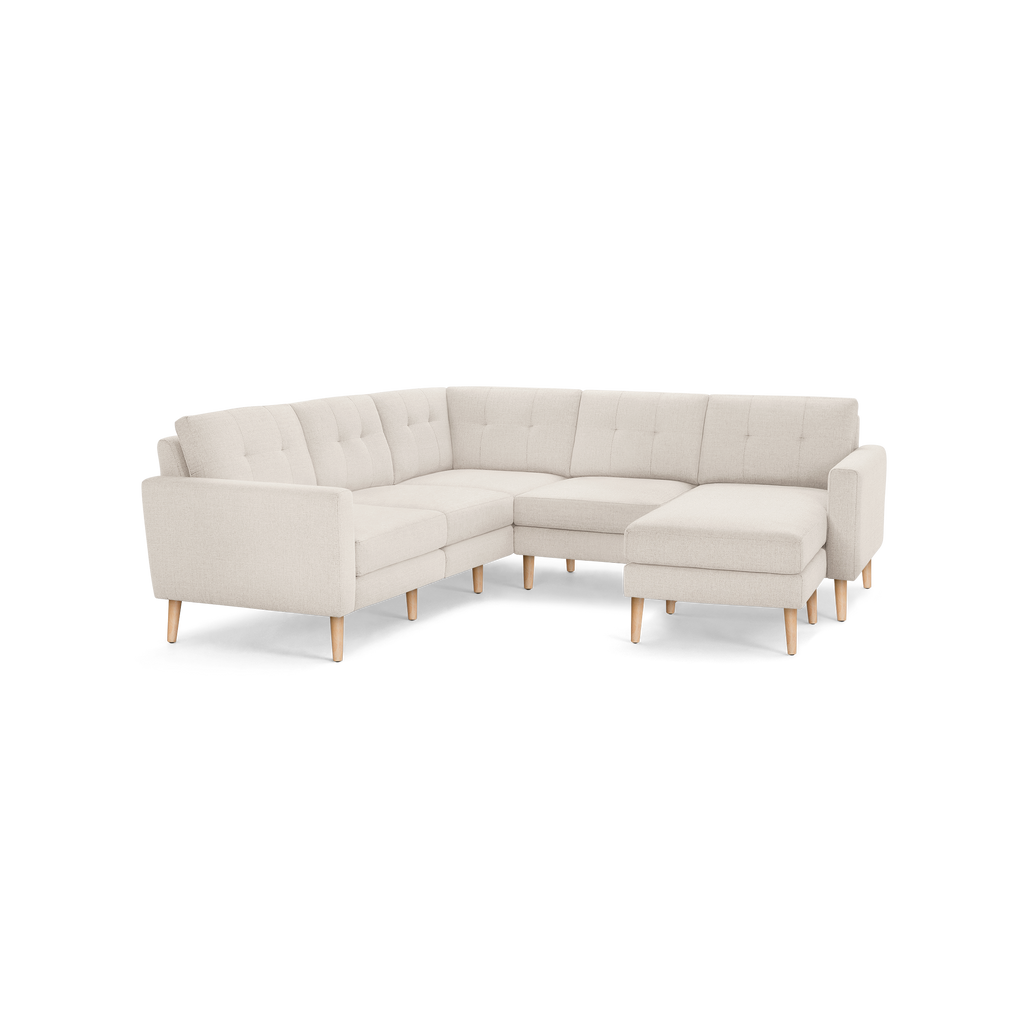 Beige fabric L-shaped sectional sofa with tufted back cushions and natural wood tapered legs.