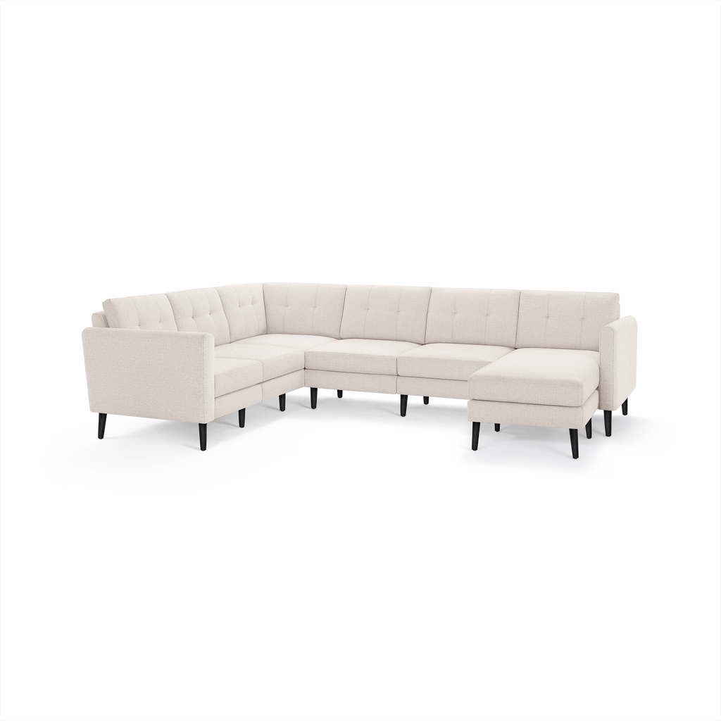 Beige L-shaped sectional sofa with tufted back cushions, slim black legs, and a right-side chaise lounge.