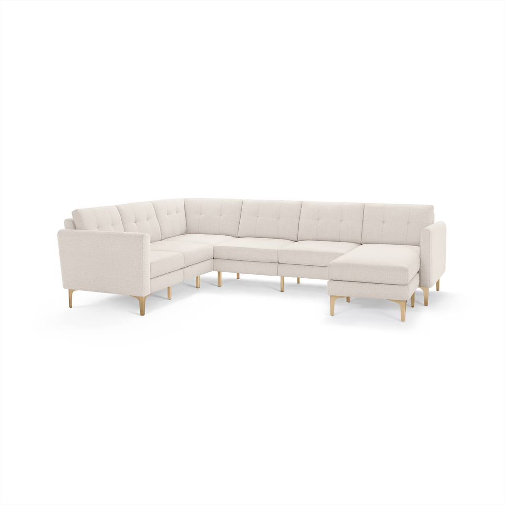Beige L-shaped sectional sofa with tufted cushions and light wooden legs, designed for spacious living room seating.