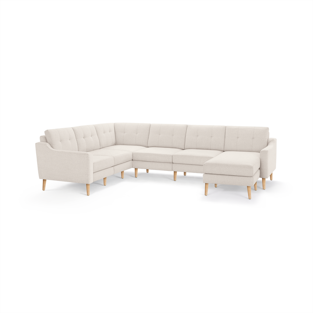Cream-colored L-shaped sectional sofa with tufted back cushions and wooden tapered legs, featuring a right-side chaise lounge.