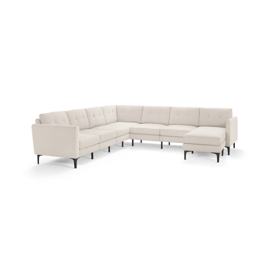 Light beige L-shaped sectional sofa with tufted back cushions, slim black legs, and a modern minimalist design.