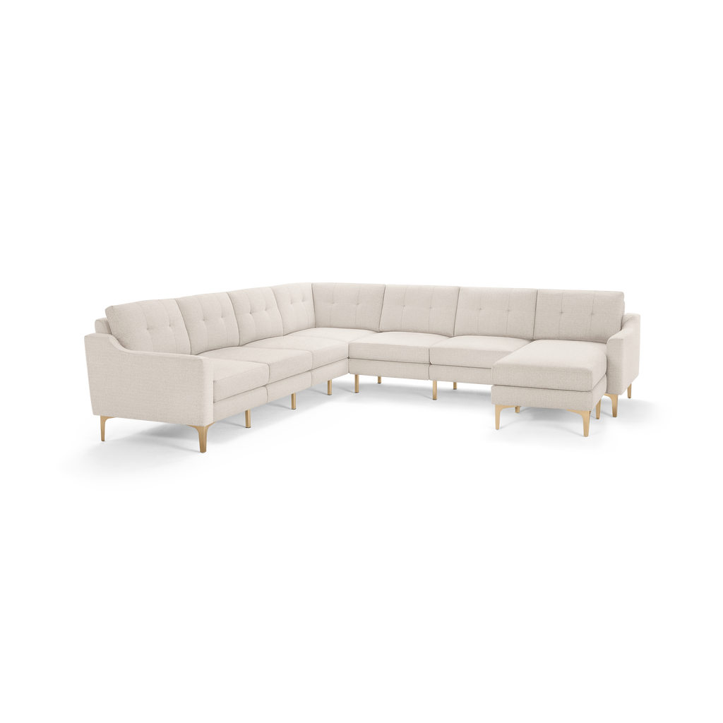 Beige L-shaped sectional sofa with tufted back cushions, slim armrests, and light wooden legs on a white background.