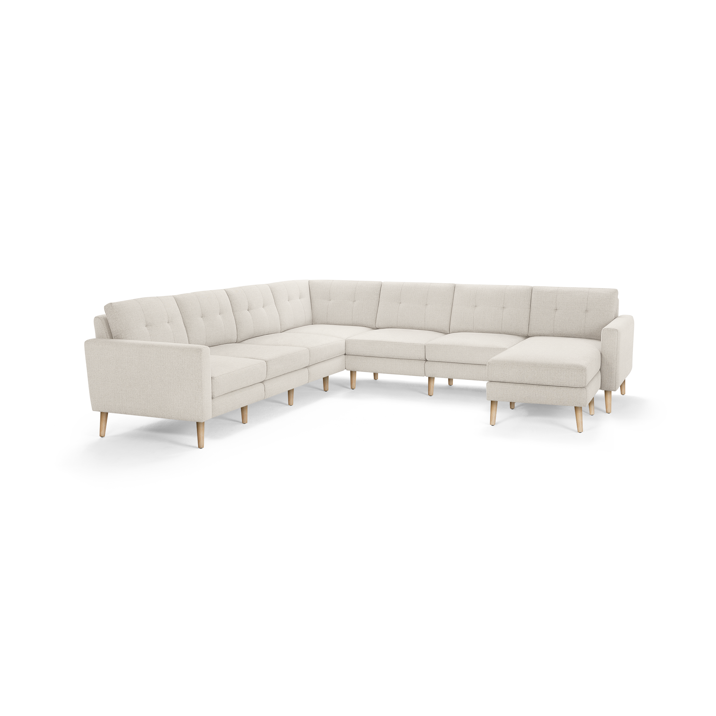 Large beige fabric sectional sofa with tufted back cushions, wooden legs, and an L-shaped design featuring a chaise lounge.