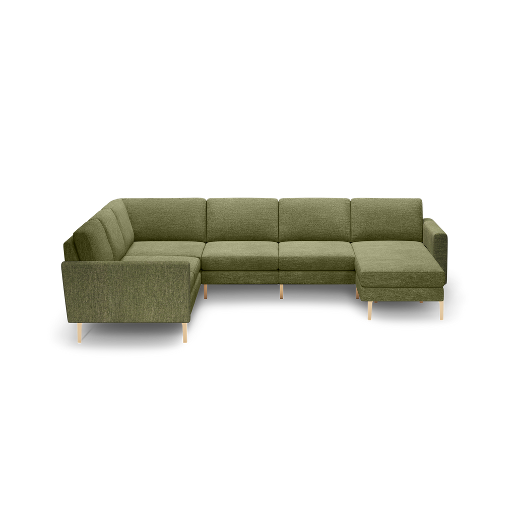 Olive green fabric sectional sofa with chaise lounge, straight arms, cushioned backrests, and light wooden legs on black background.