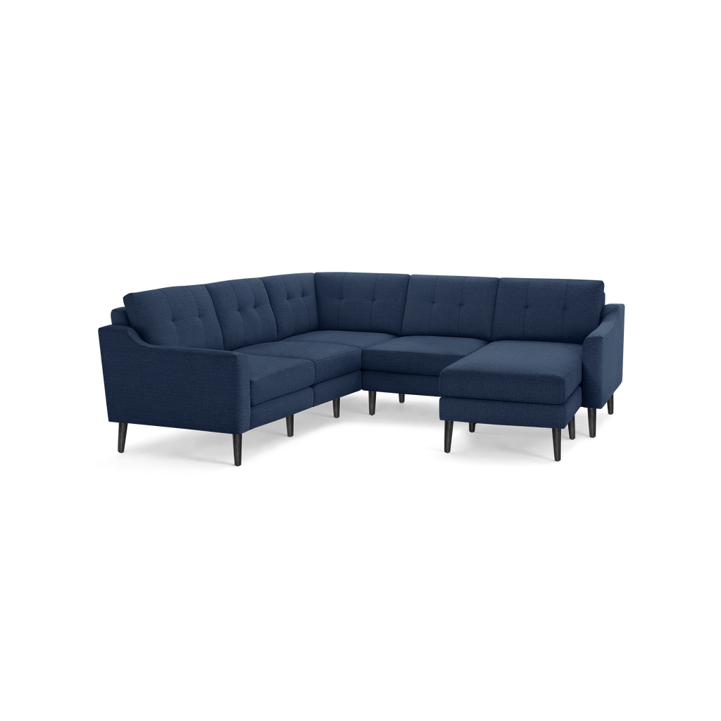 Modern L-shaped sectional sofa in dark blue fabric with tufted back cushions and slender black legs.