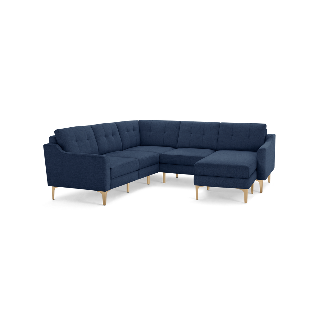 Modern navy blue L-shaped sectional sofa with tufted cushions and light wooden legs, featuring a chaise on the right side.