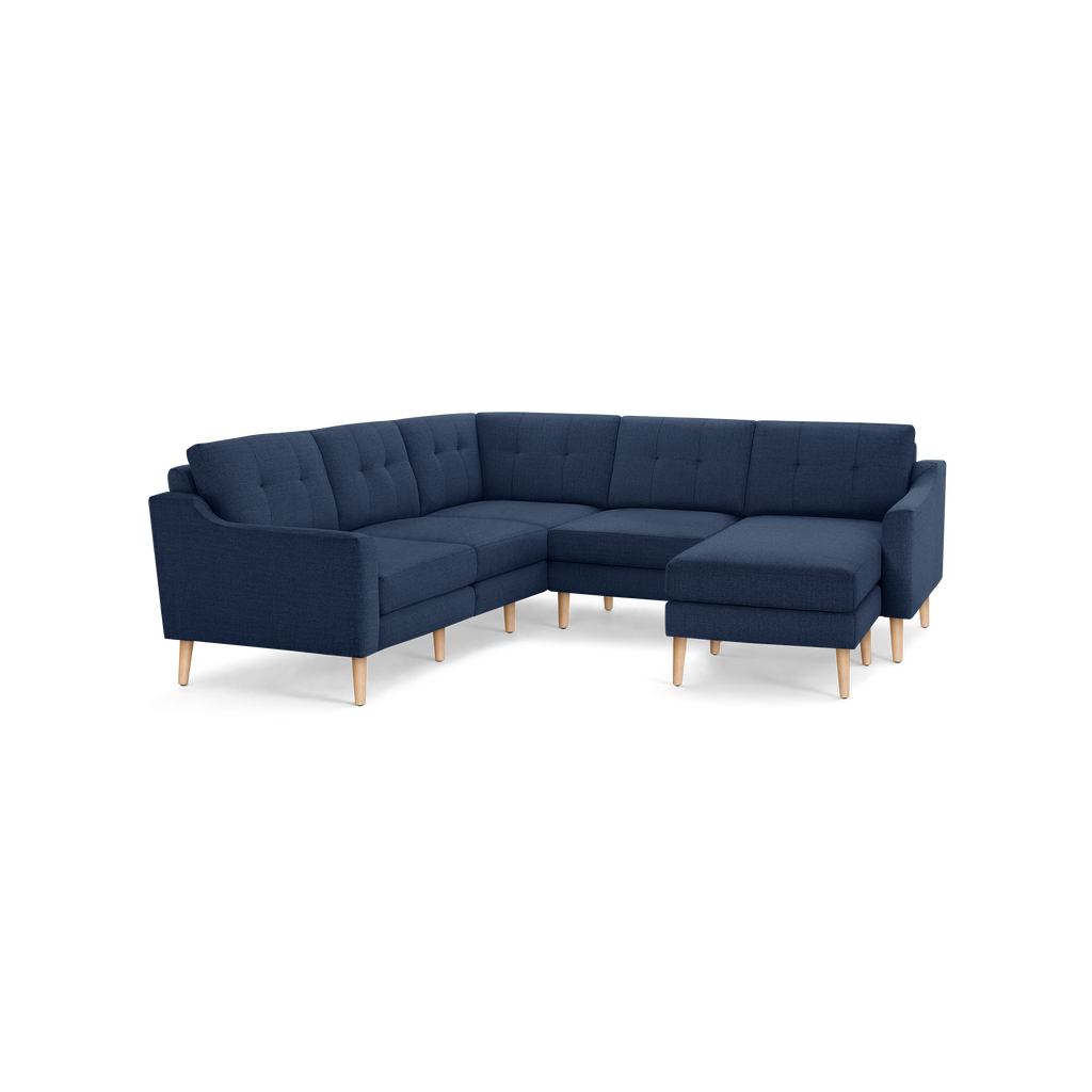 Modern L-shaped navy blue fabric sectional sofa with tufted back cushions and light wooden legs, designed for spacious seating.