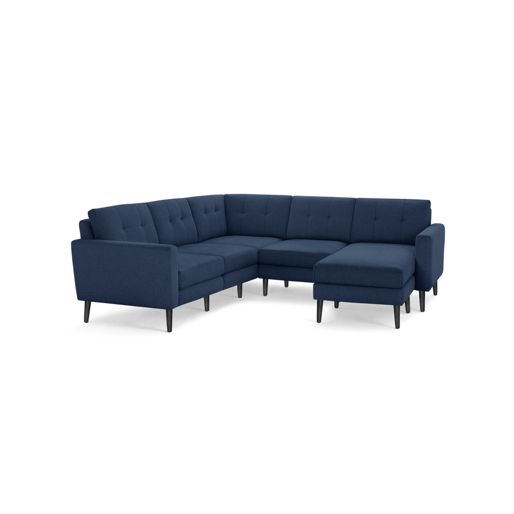Modern L-shaped sectional sofa with navy blue tufted fabric upholstery and black tapered wooden legs.