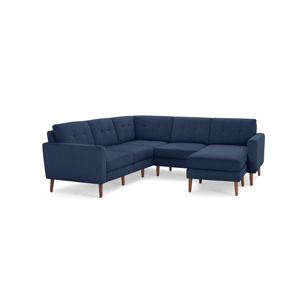 Dark blue fabric sectional sofa with tufted back cushions, wooden legs, and a right-side chaise lounge.