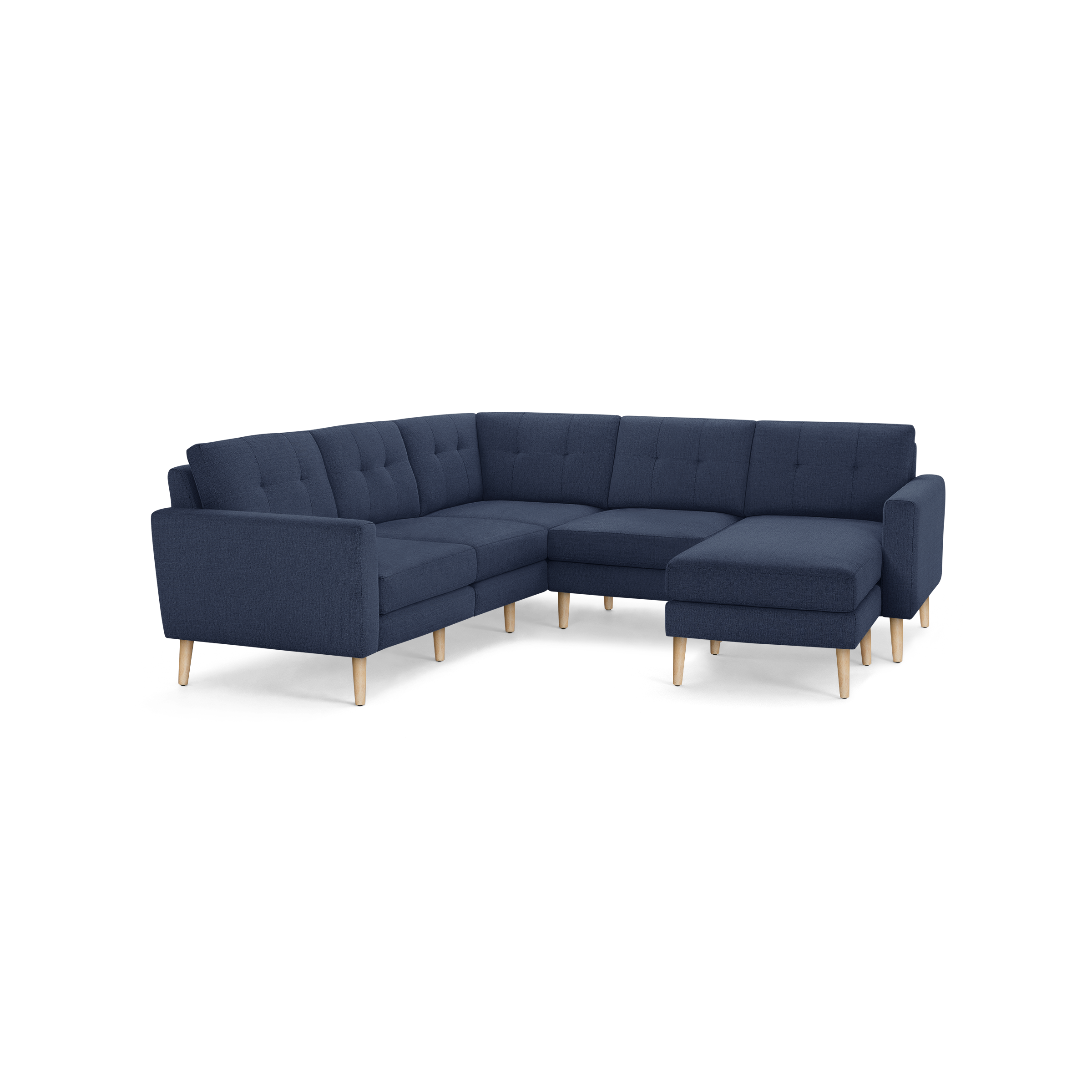 Modern L-shaped sectional sofa with dark blue fabric upholstery and light wooden legs, featuring tufted back cushions and a chaise lounge on the right side.