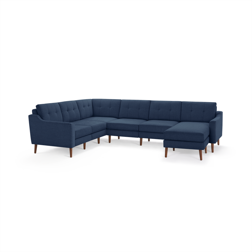 Large navy blue L-shaped sectional sofa with tufted back cushions and wooden legs on white background.