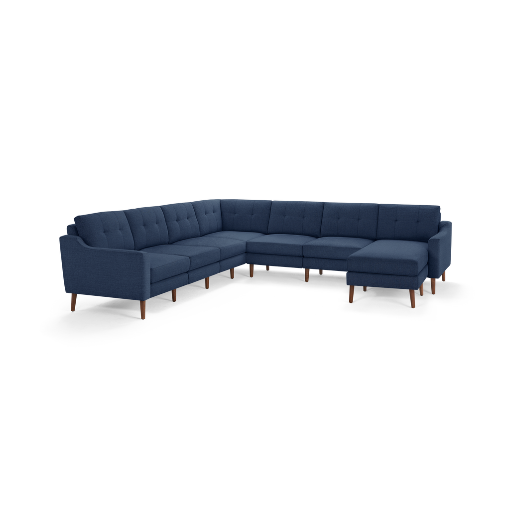 Large navy blue L-shaped sectional sofa with tufted back cushions and wooden legs, designed for spacious living rooms.